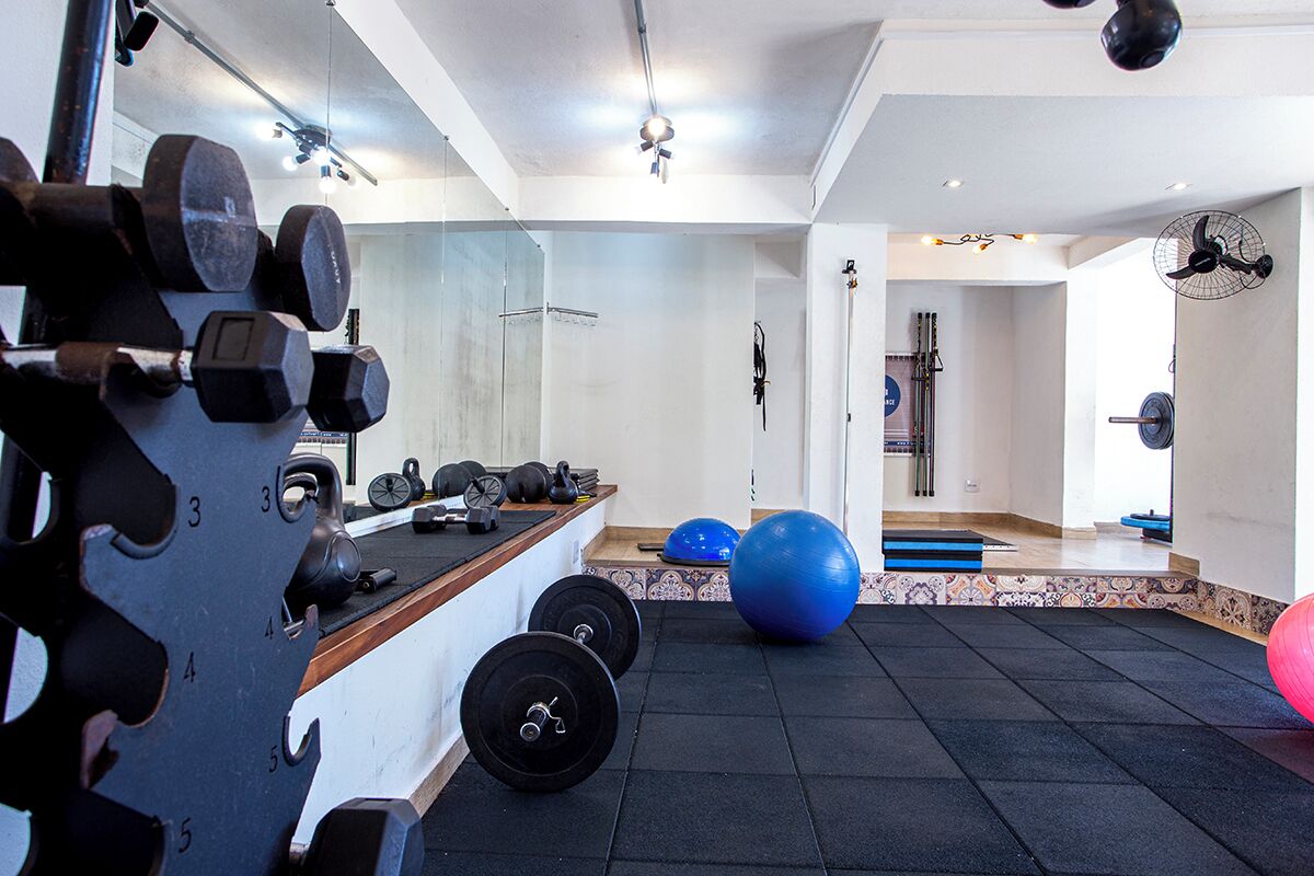 A gym with weightlifting equipment, exercise balls, and a mirror.
