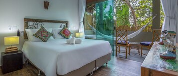 Un dormitorio con una cama grande, lámparas de noche, una mesita de noche de madera y vistas al exterior a través de una ventana con cortina.