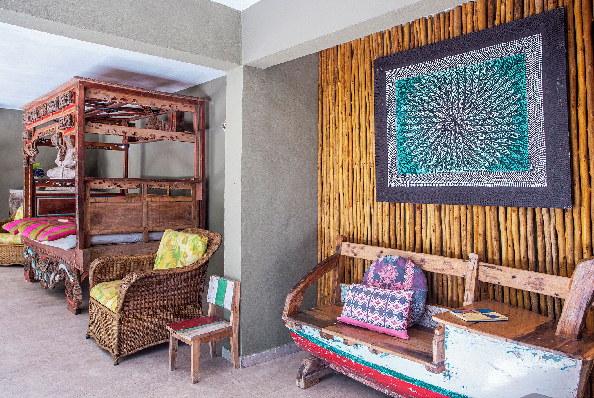 A traditional wooden bed with intricate carvings, a wicker chair with colorful cushions, and a wall with a geometric tapestry.