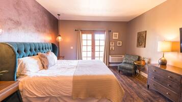 Quarto com cama grande, uma cadeira, penteadeira e janela com cortinas.