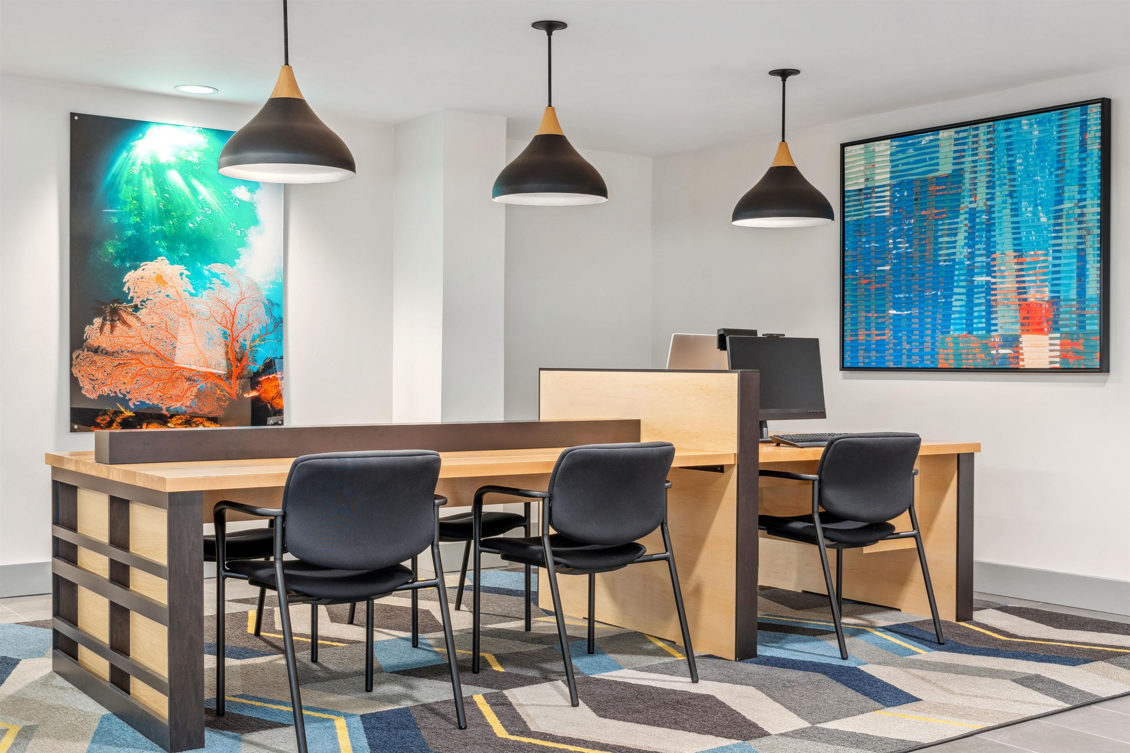 Un espace de bureau moderne avec une longue table, quatre chaises et trois lampes suspendues.