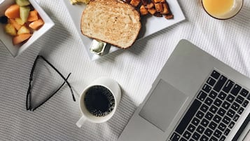 A breakfast spread on a table with waffles, scrambled eggs, bacon, toast, and fruit.