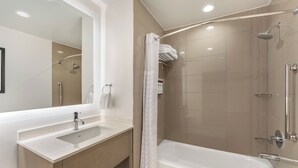 Une salle de bain moderne avec un grand miroir, un lavabo, une baignoire et une douche.