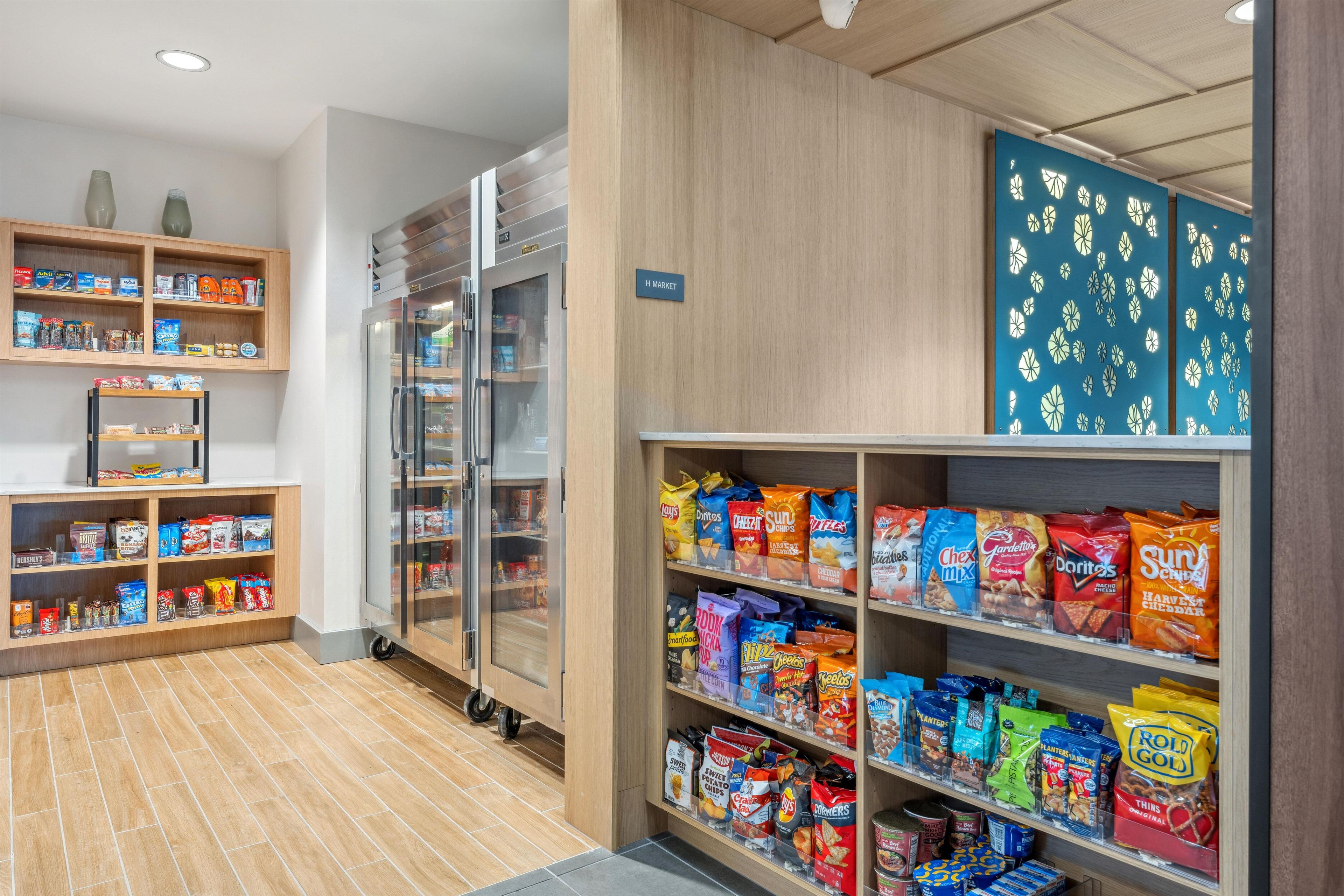 Pasillo de productos de snack con diversas opciones envasadas y un refrigerador.