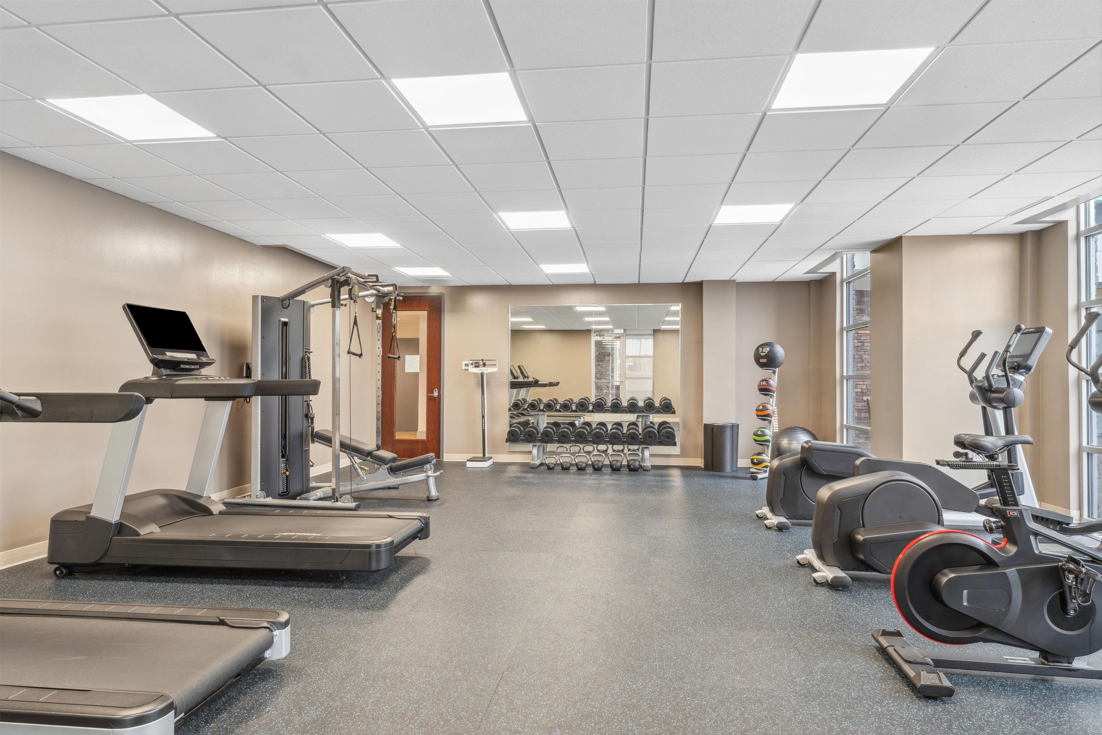 A gym with treadmills, elliptical machines, and free weights.