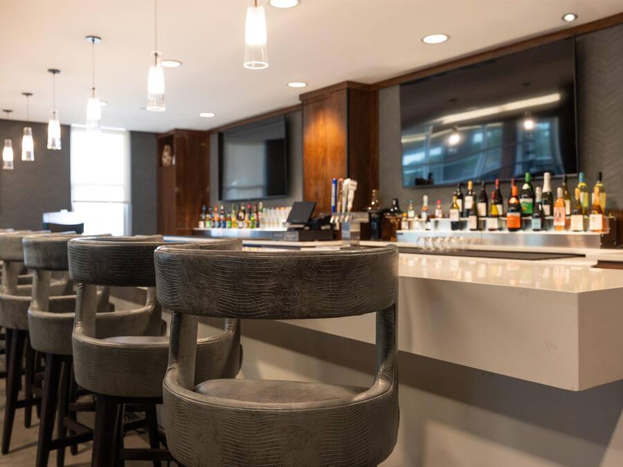 A bar area with multiple bar stools and a counter displaying various bottles.