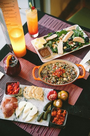 Une table où l’on trouve une variété d’aliments, notamment une salade, un bol de soupe, ainsi que différents types de fromages et de viandes.