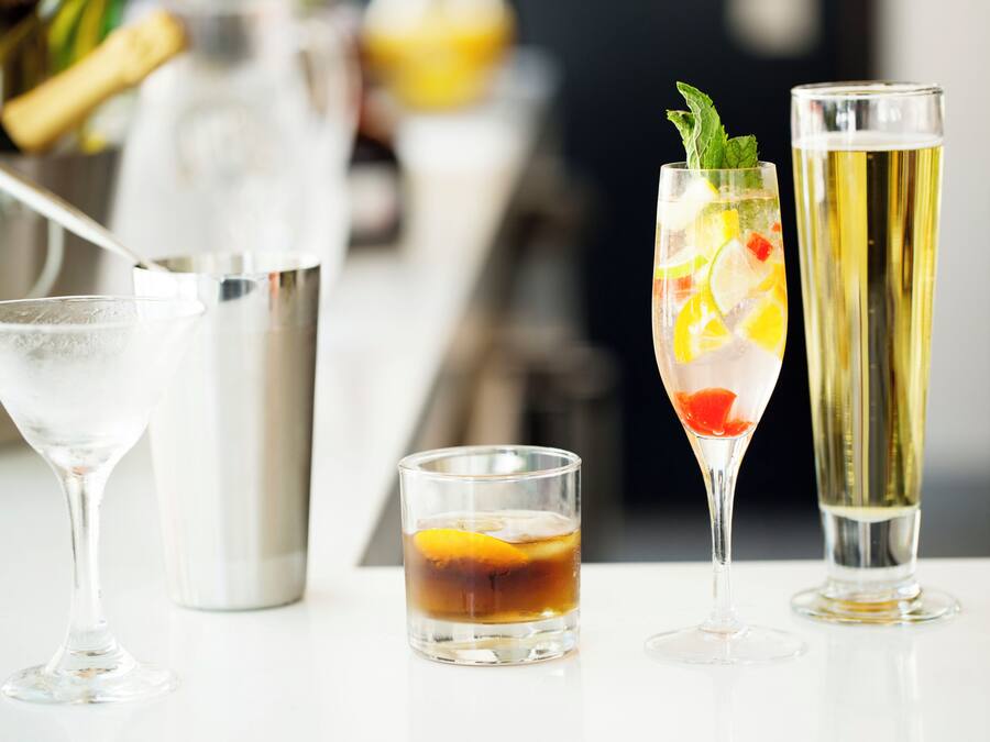 Three different types of glasses on a table, including a martini glass, a short tumbler, and a tall champagne flute.