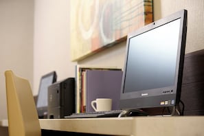 Un escritorio con un monitor Lenovo, teclado y ratón. Hay una silla frente al escritorio.
