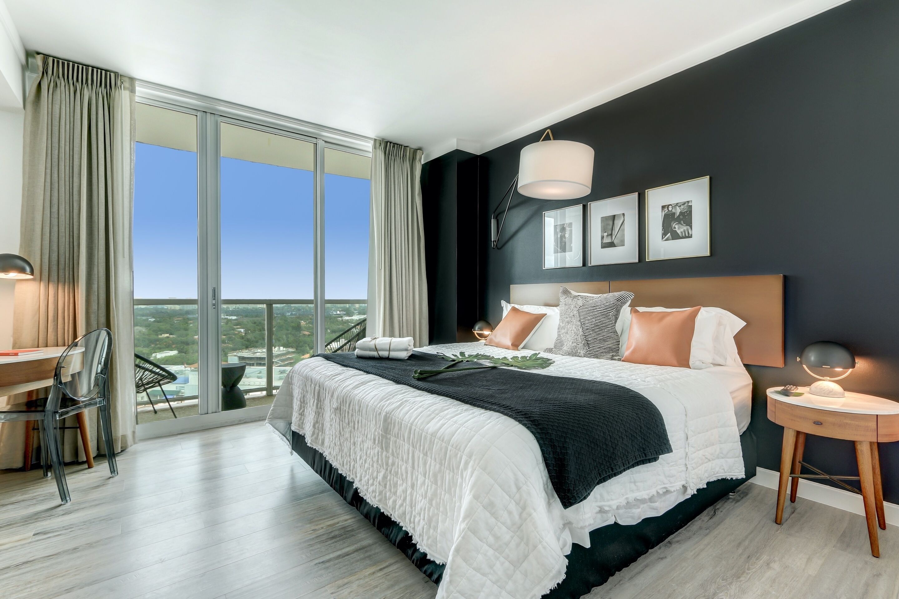 Un dormitorio moderno con una cama grande, un escritorio y vistas a la ciudad.