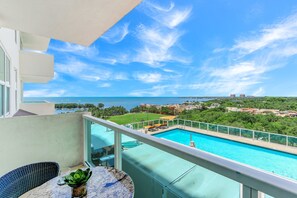A balcony with a view of a swimming pool, a grassy area, and distant buildings. - iCoconutGrove Vacation Rentals (Miami)