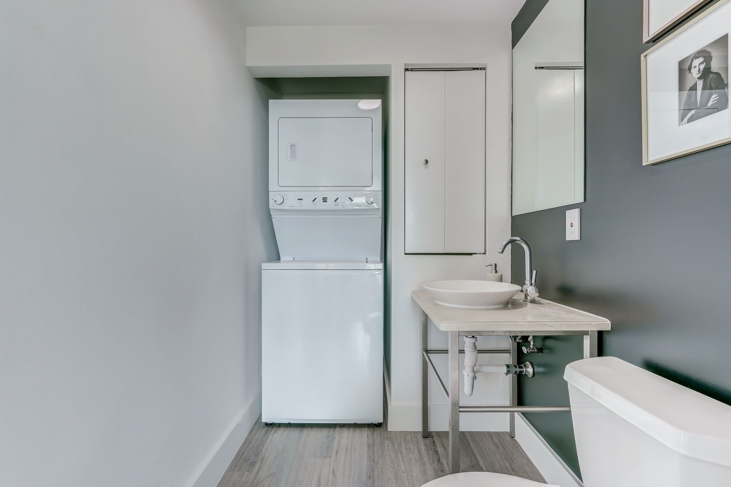 Une petite salle de bain avec des toilettes blanches, un lavabo et un lave-linge encastré.