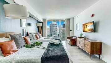 Ein modernes Hotelzimmer mit einem großen Bett, einer Holzkommode und Blick auf die Stadt.