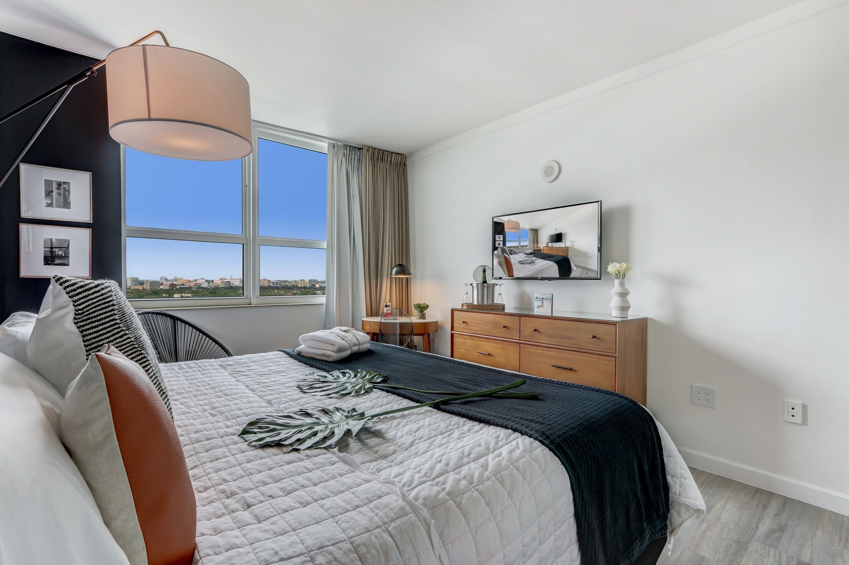 Quarto moderno com uma cama grande, uma escrivaninha, um penteado e uma televisão na parede.