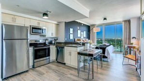 A modern kitchen with stainless steel appliances, a dining area with a table and chairs, and a balcony with a city view. - iCoconutGrove Vacation Rentals (Miami)
