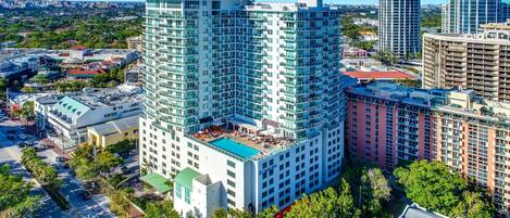 A high-rise hotel with multiple floors, a rooftop pool, and a view of the surrounding cityscape.