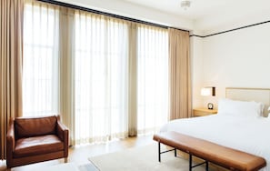 Relax in this serene space with a large bed, bedside table, and comfortable armchair.