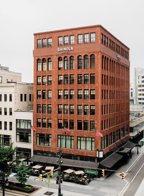A red brick building with the name 'Shinola Hotel' on the facade, featuring multiple windows and a corner entrance. - Shinola Hotel (Detroit)