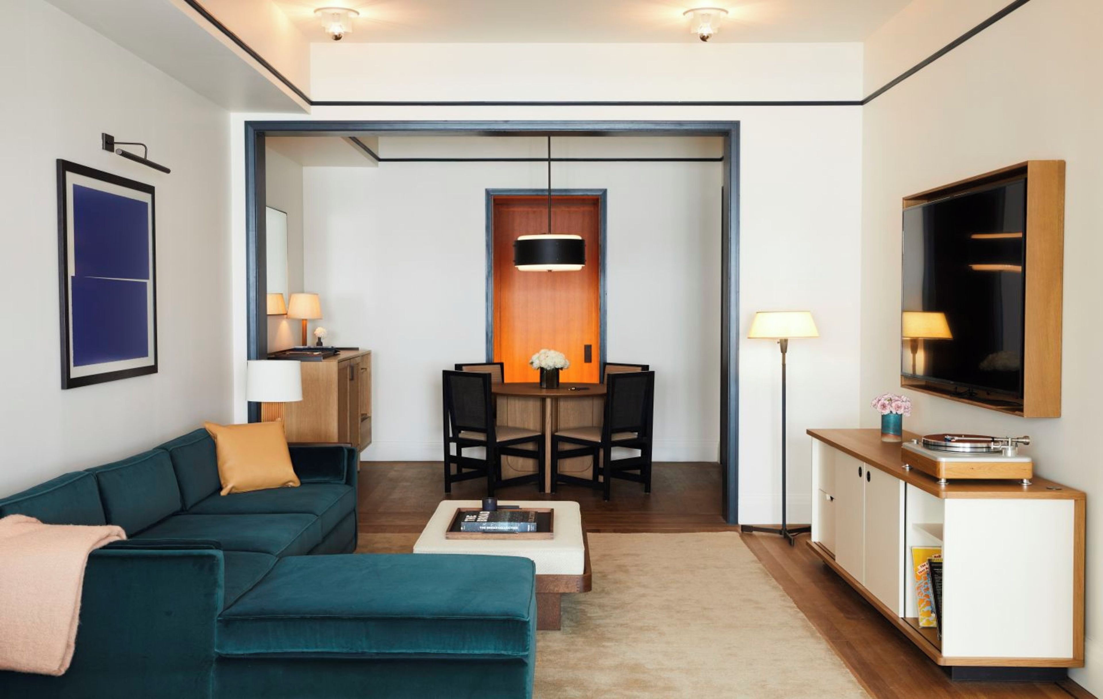 Un salon moderne avec un canapé de couleur turquoise, une table basse et un coin repas comprenant une table et des chaises en bois.