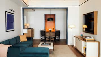 Un salon moderne avec un canapé de couleur turquoise, une table basse et un coin repas comprenant une table et des chaises en bois.