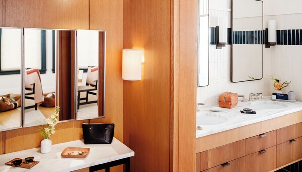 A modern bathroom with wooden paneling, a white marble countertop, a large mirror, and a vanity with a sink and toiletries.