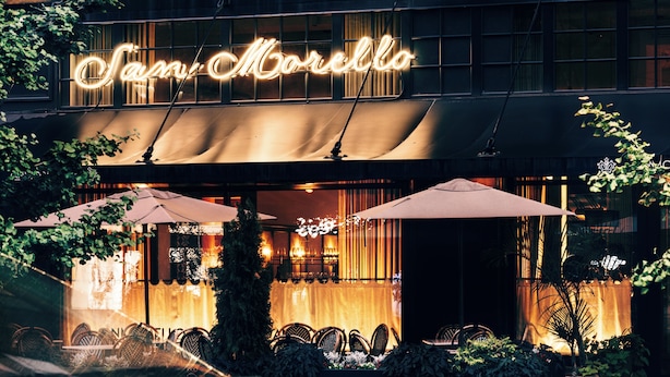 Un restaurant doté d'une terrasse, d'une enseigne au néon et d'un patio couvert.