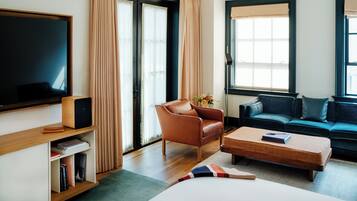A modern living room with a flat-screen TV, leather armchair, sofa, and a coffee table.