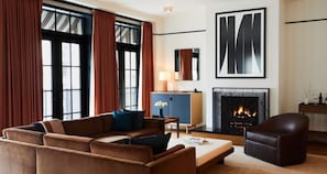 A modern living room with a sofa set, a fireplace, and large windows with curtains. - Shinola Hotel (Detroit)