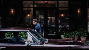 L’entrée d’un hôtel, avec une voiture classique garée devant.