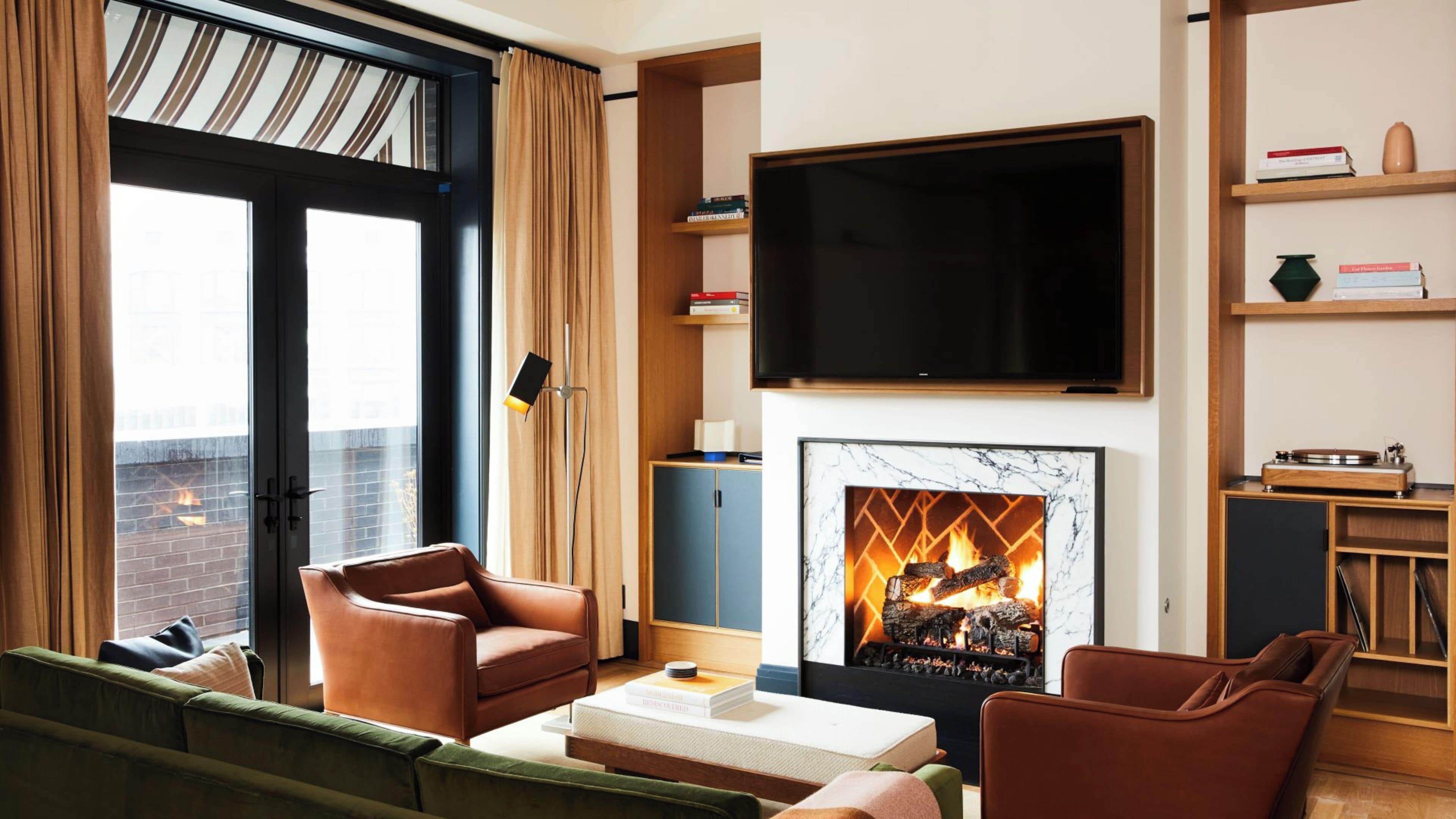 Una sala moderna con chimenea, sofás de cuero, un televisor de pantalla plana y una estantería.