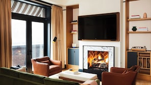 Una sala moderna con chimenea, sofás de cuero, un televisor de pantalla plana y una estantería.