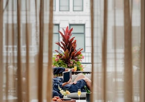 A person reclining on a sofa with a laptop, a glass of orange juice, and a bottle of champagne on a table.