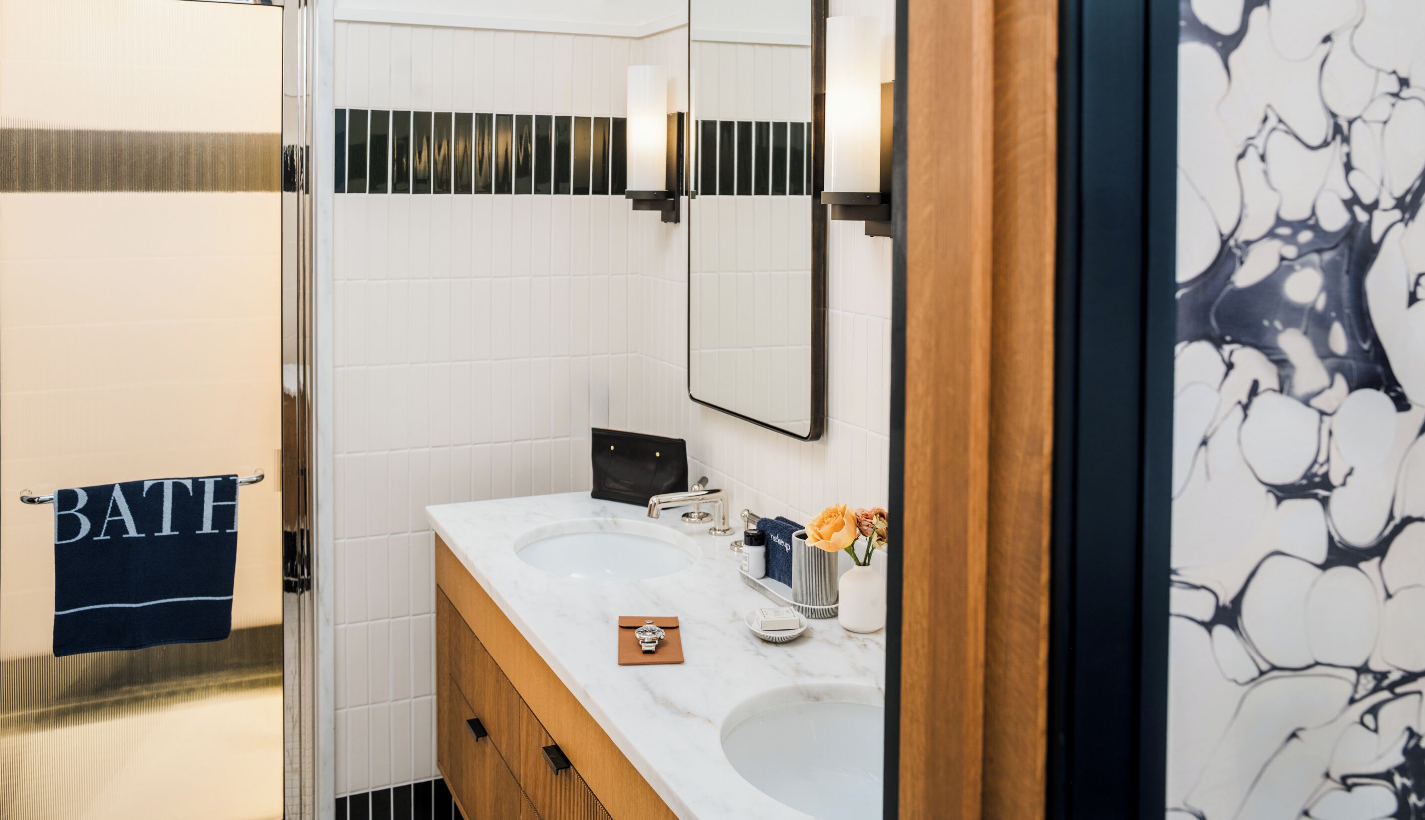 Une salle de bain avec un lavabo blanc, un miroir et un porte-serviettes sur lequel est posée une serviette étiquetée « BAIN ».