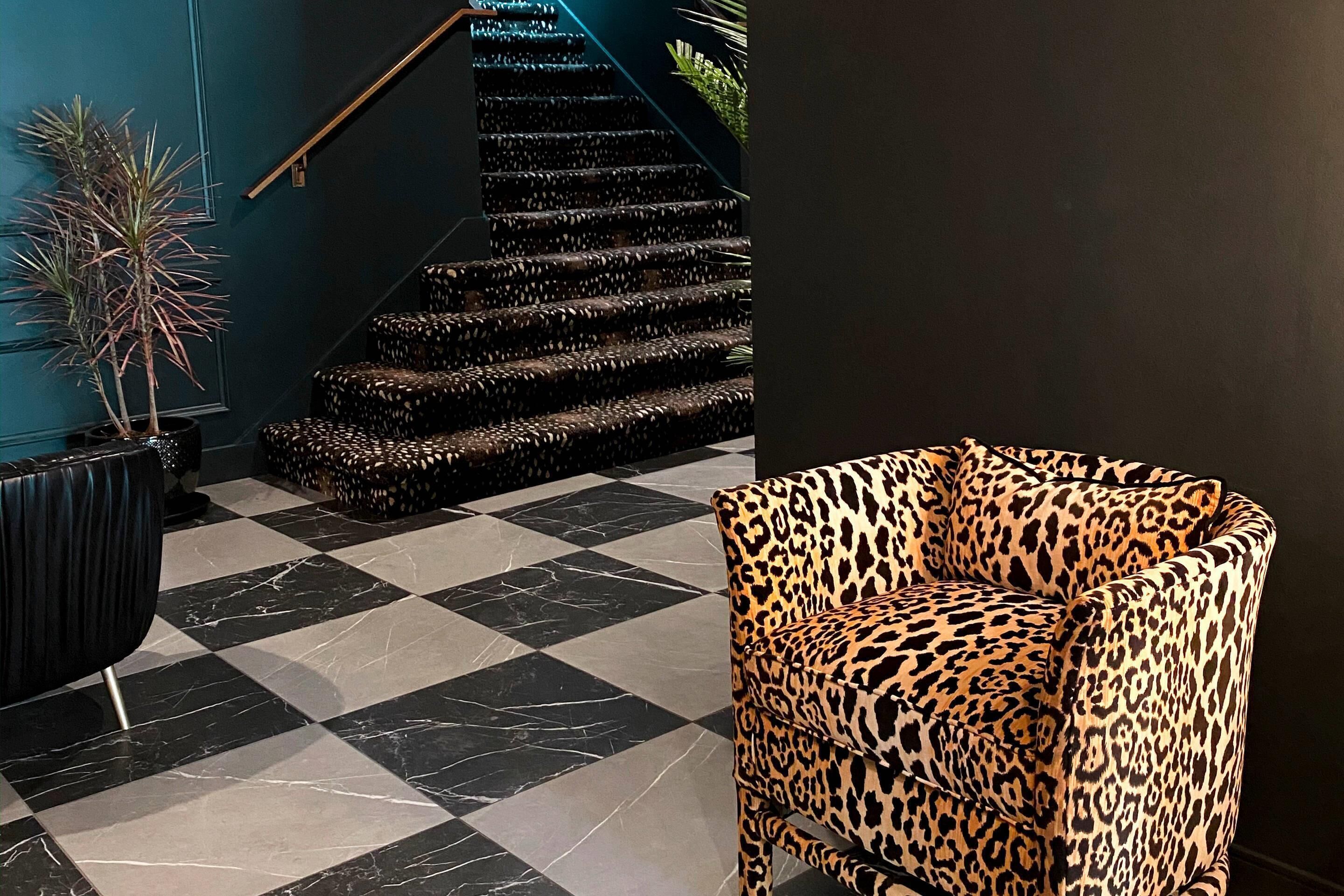 Piso xadrez com escada e uma poltrona com estampa de leopardo.