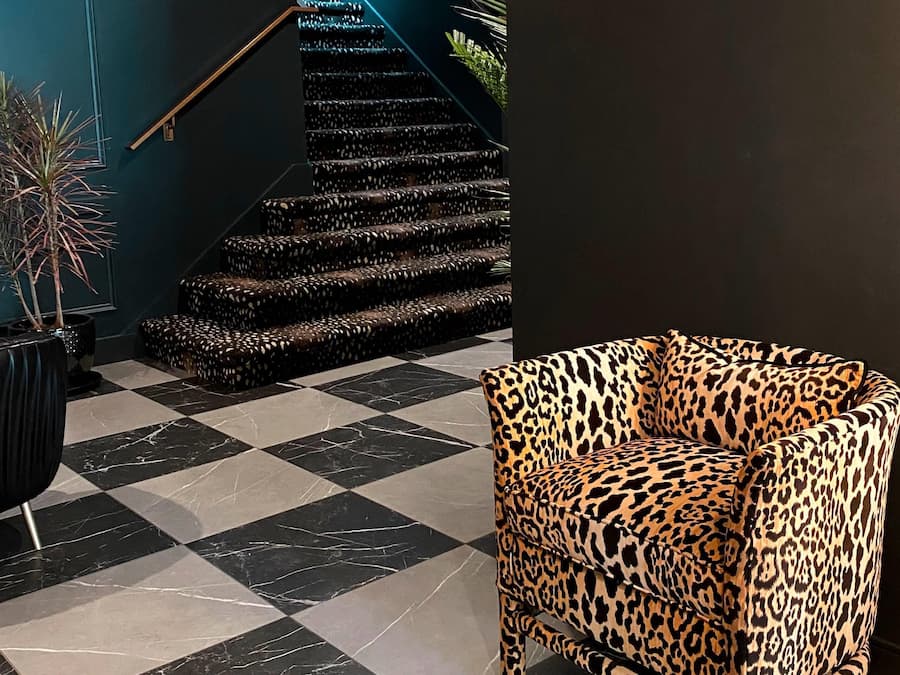 Piso xadrez com escada e uma poltrona com estampa de leopardo.