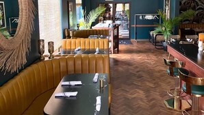 A restaurant with a herringbone wood floor, leather booths, and a bar area with stools. - The Inn Hotel Lake Okoboji, an Ascend Collection Hotel (Arnolds Park)