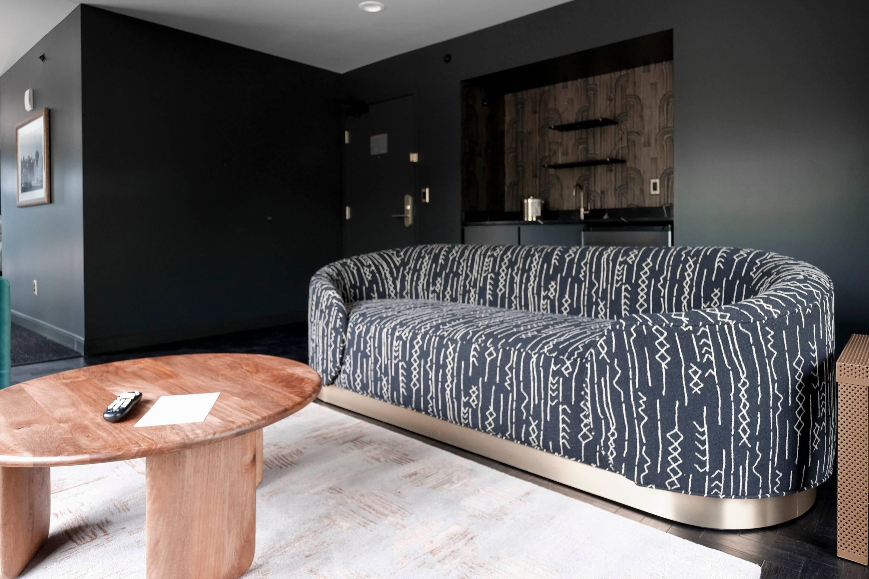 A modern living room with a dark-colored sofa, a wooden coffee table, and a minimalist design.