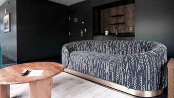A modern living room with a dark-colored sofa, a wooden coffee table, and a minimalist design.
