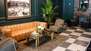A room with a leather sofa, patterned chairs, a coffee table with books and flowers, a large framed photograph on the wall, and a checkered floor. - The Inn Hotel Lake Okoboji, an Ascend Collection Hotel (Arnolds Park)