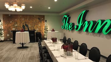 Una sala de conferencias con una larga mesa dispuesta para una reunión, una pared con el letrero iluminado 'The Inn', y un mural con pájaros y flores.