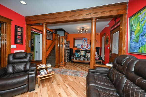 Un amplio salón con una escalera de madera, sofás de cuero y una estantería.