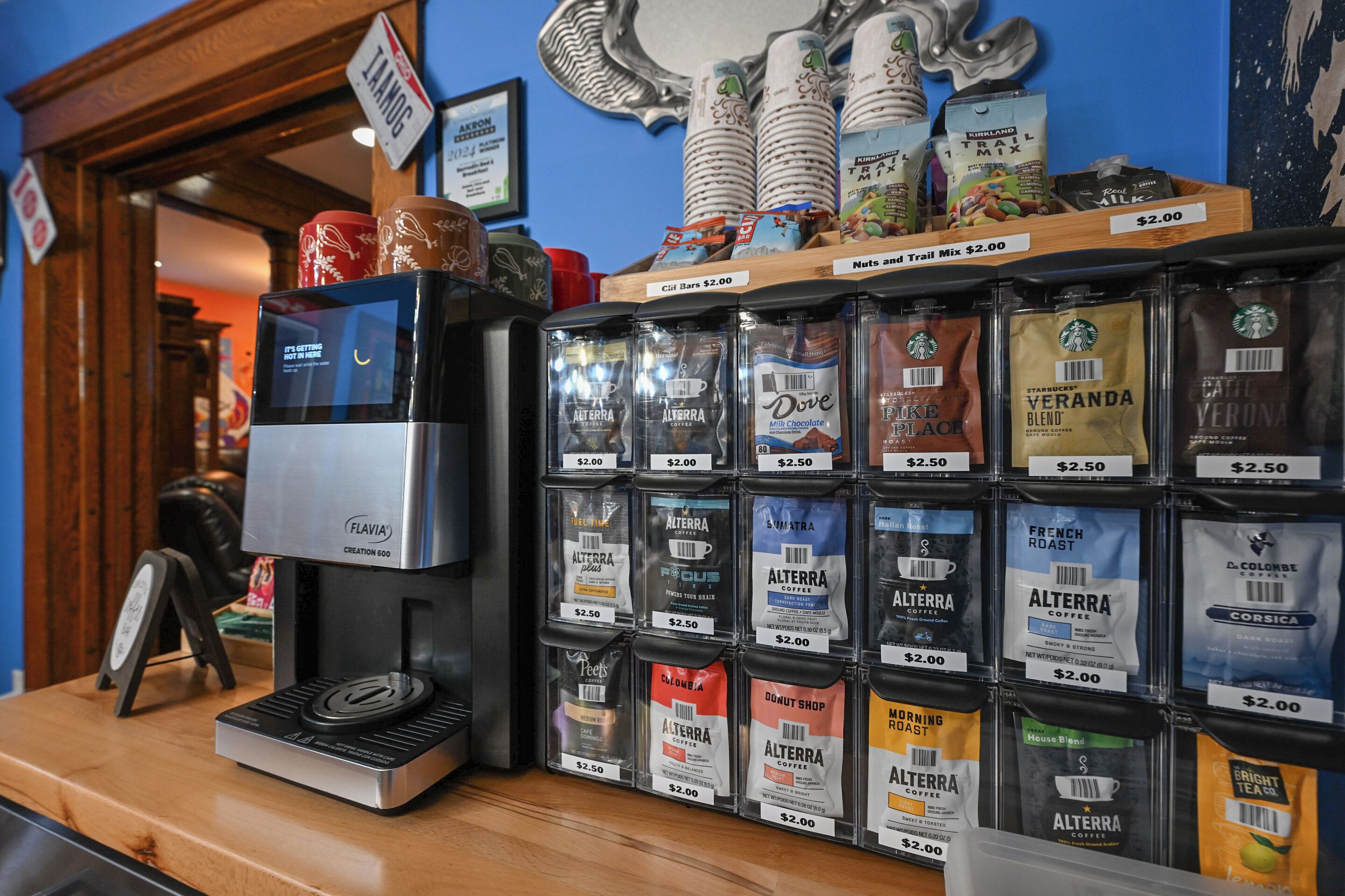Ein Tresen einer Kaffeebar mit einer Kaffeemaschine und verschiedenen Kaffeesorten, jeweils für 2,00 Dollar.