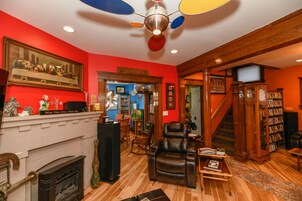 A living room with a fireplace, leather recliner, bookshelf, and a ceiling fan.