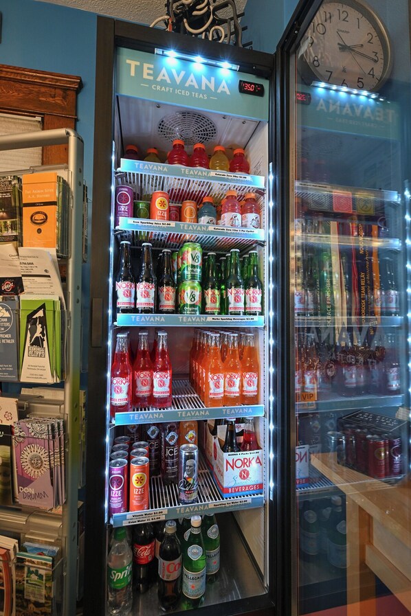Un distributeur automatique rempli de diverses boissons, notamment des sodas, des jus pétillants et des thés glacés.
