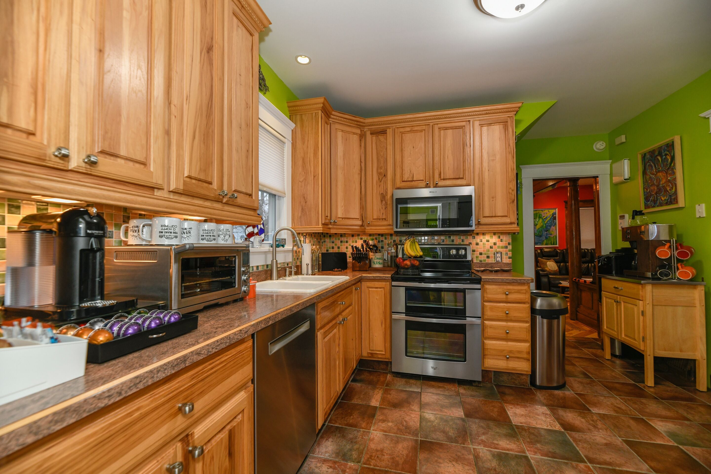 A kitchen with wooden cabinets, stainless steel appliances, and a green accent wall.