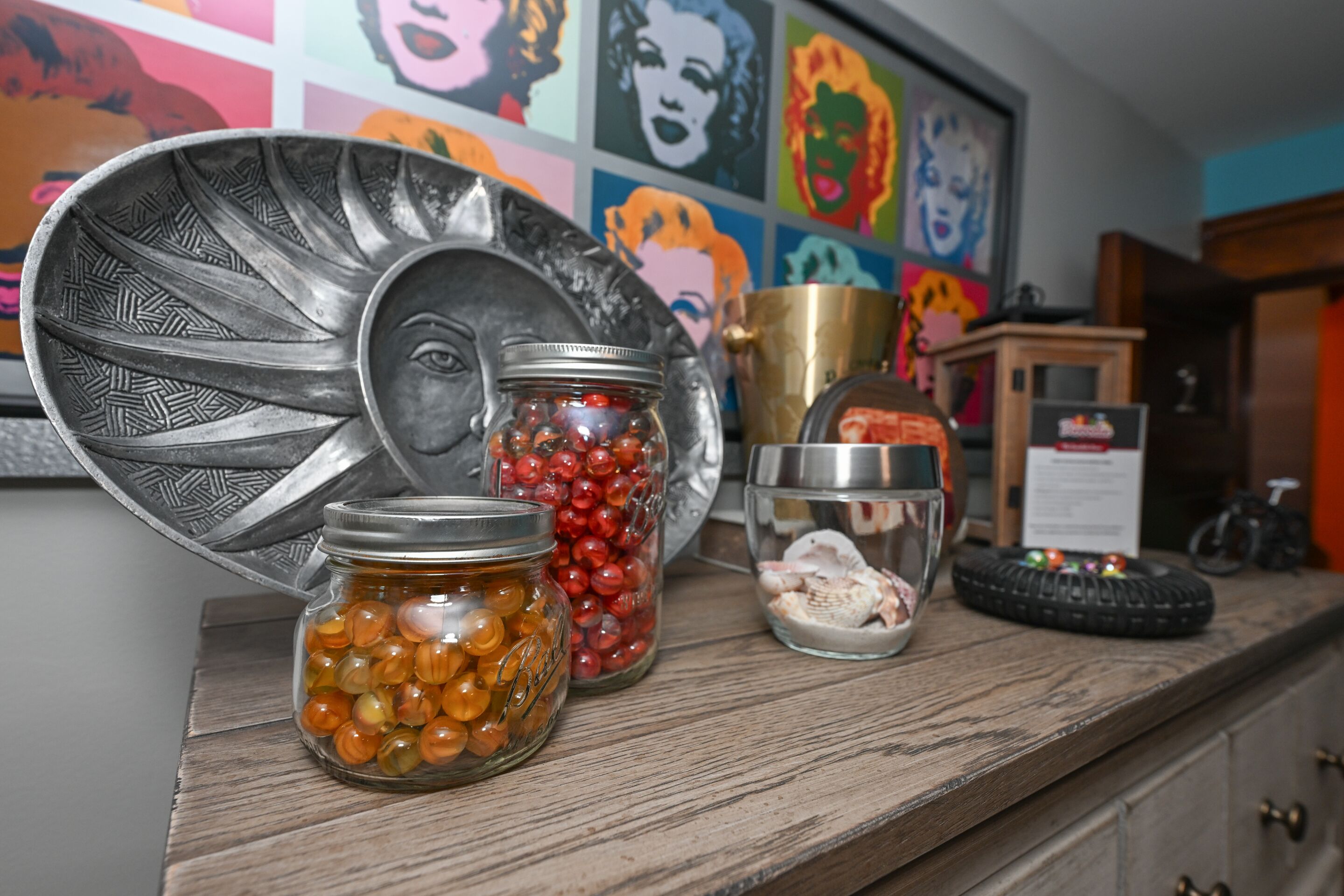 A kitchen counter with various jars containing different items, a decorative plate, and a bicycle in the background.