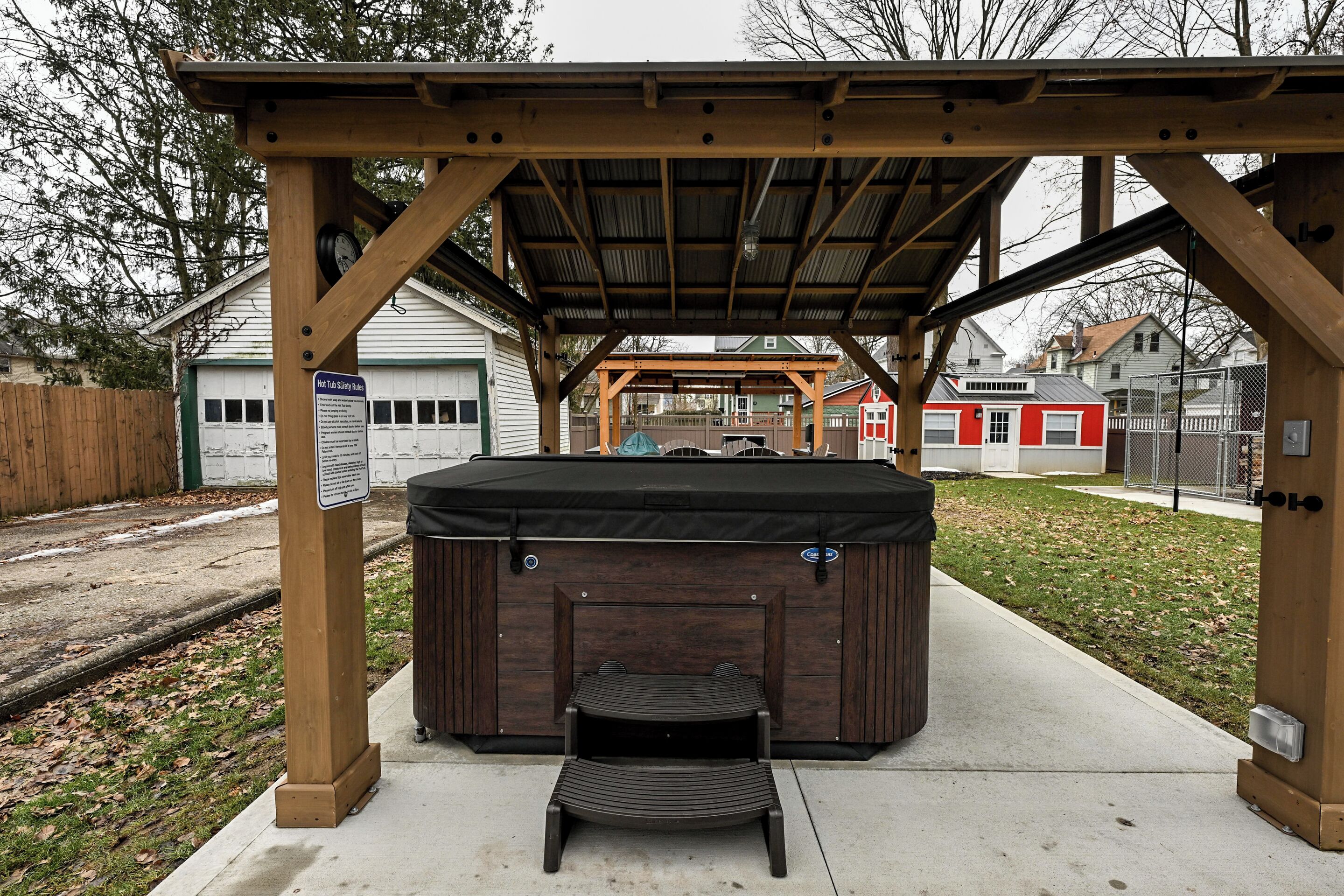 Un bain à remous sous une pergola en bois, avec un espace patio couvert.