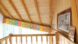 Eine Holztreppe mit Geländer, eine Reihe bunter Plakate an der Wand und ein gerahmtes Bild.