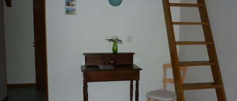 A room with a desk, chair, and a wooden ladder.