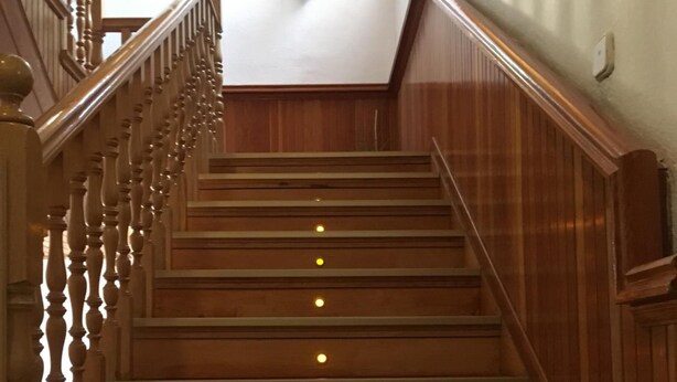 Eine Holztreppe mit Handlauf und einem Blumentopf oben.